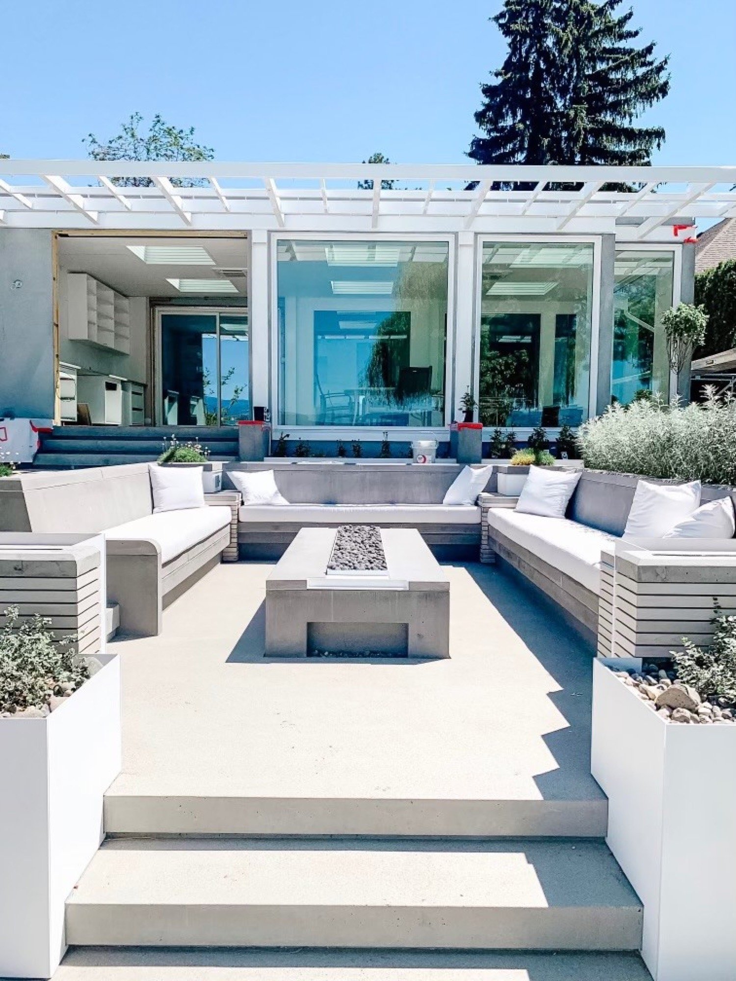 Sunken concrete lounge with fire table and white pergola